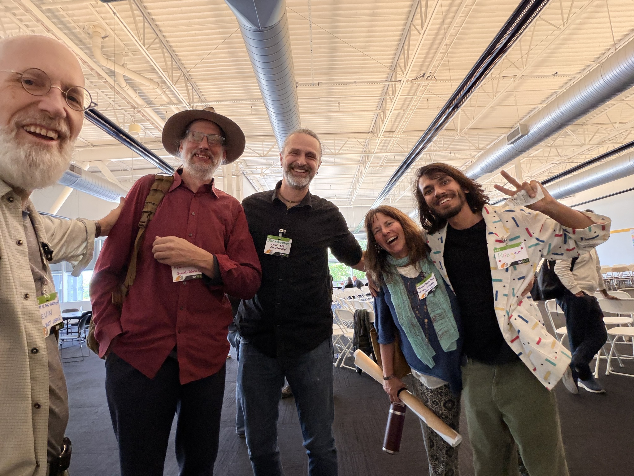 Tracey with four other participants at the Internet Identity Workshop, holding a rolled poster, all smiling.